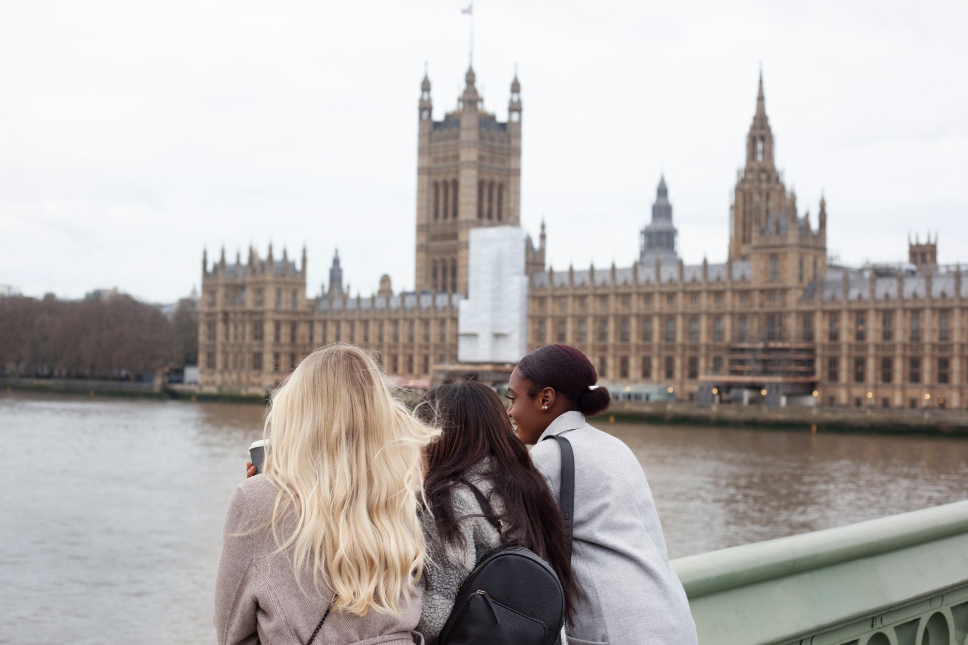 伦敦泰晤士河畔的三位年轻女子，身后是威斯敏斯特宫